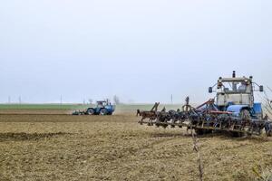 Lush and loosen the soil on the field before sowing. The tractor plows a field with a plow photo