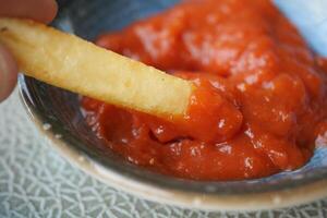 toma detallada de papas fritas bebiendo salsa en la mesa foto