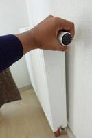 men holding temperature knob of heating radiator photo