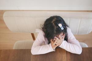 a upset child girl cover her face with hand photo