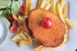 top view of Chicken schnitzel served with potato chips photo