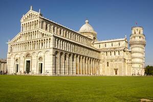 Pisa Cathedral Square with green grass on a meadow and clear blue sky on the background photo