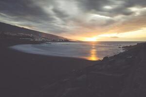 Black pebble beach in Puerto de la Cruz by the sunset , Tenerife, Canary Islands Spain photo