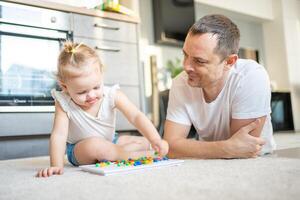 linda pequeño niña jugando con seta uña mosaico. padre y bebé jugando juntos concepto. pasatiempo y ocio tiempo. foto