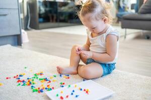 bonito pequeño niña jugando con seta uña mosaico a hogar. pasatiempo y ocio hora foto