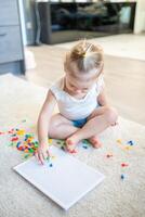 Pretty little girl playing with mushroom nail mosaic at home. Hobby and leisure time photo