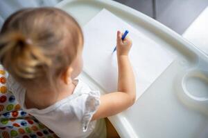 Cute little girl painting with felt-tip pen at home. Creative games for kids. Stay at home entertainment photo