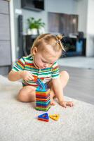 Little girl playing colorful magnet plastic blocks kit at home. The child playing educational games. Early childhood development. photo