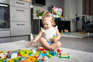 caucásico niño un pequeño niña es jugando en el constructor a hogar. educativo juguetes para niños. foto