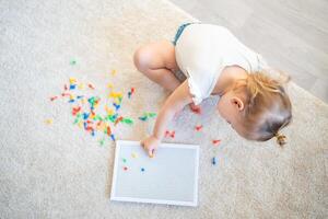 bonito pequeño niña jugando con seta uña mosaico a hogar. pasatiempo y ocio hora foto