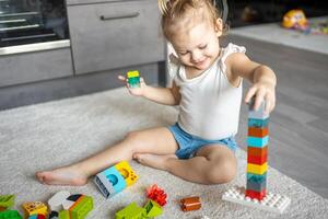 Caucasian child a little girl is playing in the constructor at home. Educational toys for children. photo