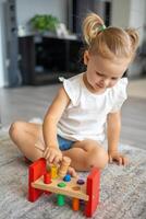 Cute caucasian little girl playing on the floor at home with eco wooden toys. The child playing educational games. photo