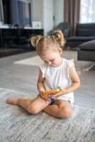 Cute little girls playing with enthusiasm pop it sensory toy circle form. Little female presses colorful rainbow squishy soft silicone bubbles at home. photo