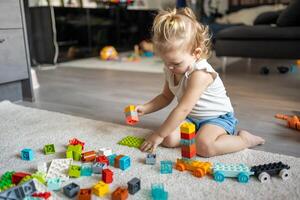 Caucasian child a little girl is playing in the constructor at home. Educational toys for children. photo