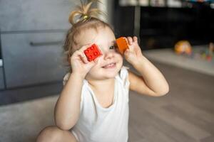 caucásico niño un pequeño niña es jugando en el constructor a hogar. educativo juguetes para niños. foto