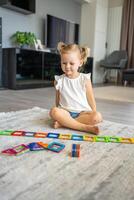 pequeño niña jugando vistoso imán el plastico bloques equipo a hogar. el niño jugando educativo juegos. temprano infancia desarrollo. foto