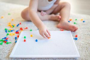 Pretty little girl playing with mushroom nail mosaic at home. Hobby and leisure time photo