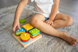 linda caucásico pequeño niña jugando en el piso a hogar con eco de madera juguetes montessori juguete. el niño jugando educativo juegos. foto