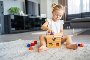 Cute caucasian little girl playing on the floor at home with eco wooden toys. The child playing educational games. photo