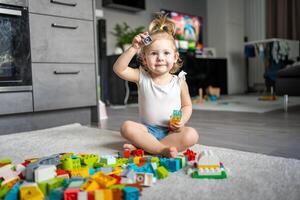 caucásico niño un pequeño niña es jugando en el constructor a hogar. educativo juguetes para niños. foto