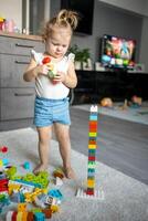 caucásico niño un pequeño niña es jugando en el constructor a hogar. educativo juguetes para niños. foto