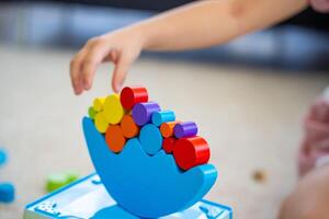 Little girl playing with wooden balancing toy on the floor in home living room. Focus on balancer photo