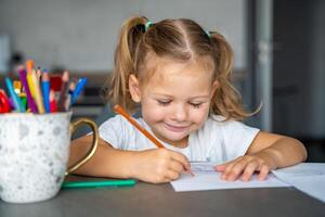 little girl draws with colored pencils in home. photo