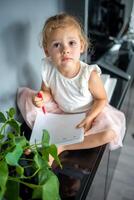 Little girl draw or write by red pencil at home. Child creativity and education concept photo