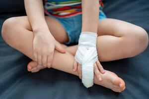 Little girl with broken finger on sofa at home on sick leave photo