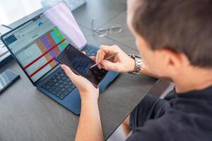 Close up view of man hand holding smart phone and stylus pen at his creative workspace. photo