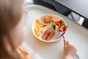 pequeño niña tener un equilibrado desayuno en hogar cocina en el Mañana foto