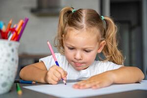 little girl draws with colored pencils in home. photo