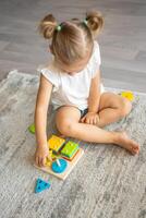 Cute caucasian little girl playing on the floor at home with eco wooden toys. The child playing educational games. photo