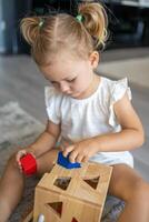 Cute caucasian little girl playing on the floor at home with eco wooden toys. Montessori toy. The child playing educational games. photo