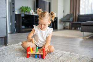 linda caucásico pequeño niña jugando en el piso a hogar con eco de madera juguetes montessori juguete. el niño jugando educativo juegos. foto