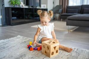 linda caucásico pequeño niña jugando en el piso a hogar con eco de madera juguetes montessori juguete. el niño jugando educativo juegos. foto