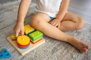 linda caucásico pequeño niña jugando en el piso a hogar con eco de madera juguetes montessori juguete. el niño jugando educativo juegos. foto