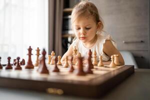 pequeño niña jugando ajedrez a el mesa en hogar cocina. el concepto temprano infancia desarrollo y educación. familia ocio, comunicación y recreación. foto
