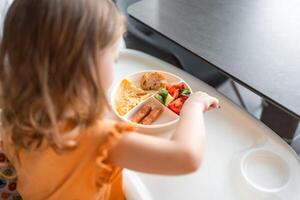 pequeño niña tener un equilibrado desayuno en hogar cocina en el Mañana foto