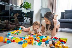 Little girl play with constructor toy on floor in home with mom or woman babysitter, educational game, family at home spend leisure activities time together concept photo