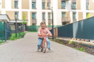 pequeño niña montando equilibrar bicicleta en el patio de el residencia en praga, Europa foto