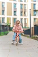 Little girl riding balance bike in the courtyard of the residence in Prague, Europe photo