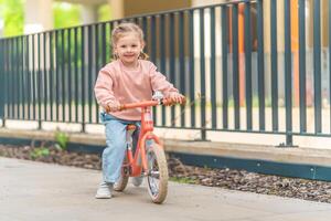 pequeño niña montando equilibrar bicicleta en el patio de el residencia en praga, Europa foto