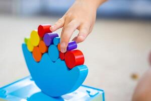 Little girl playing with wooden balancing toy on the floor in home living room. Focus on balancer photo