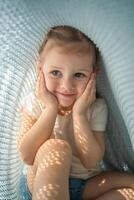pequeño niña tener un divertido debajo azul de punto tartán en soleado Mañana foto
