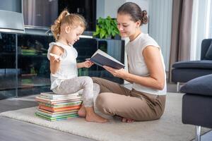 joven madre es leyendo un libro a su sonriente hija. foto