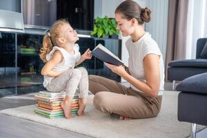 Young mother is reading a book to her cute daughter. photo