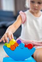 Little girl playing with wooden balancing toy on the floor in home living room. Focus on balancer photo