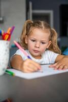 little girl draws with colored pencils in home. photo