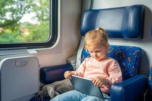 Beautiful Little girl using digital tablet during traveling by railway, Europe photo